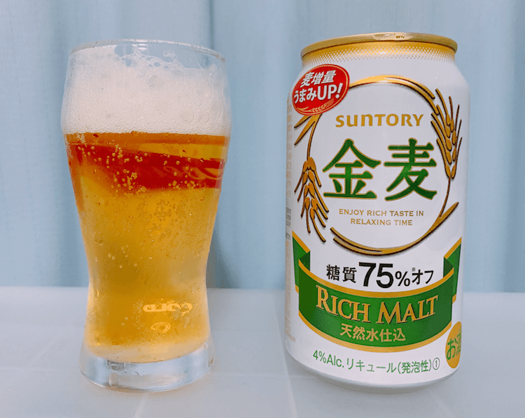 左にビールが入れられているグラス、右に緑色で金麦と記載されている350mlのビール缶が置かれている
