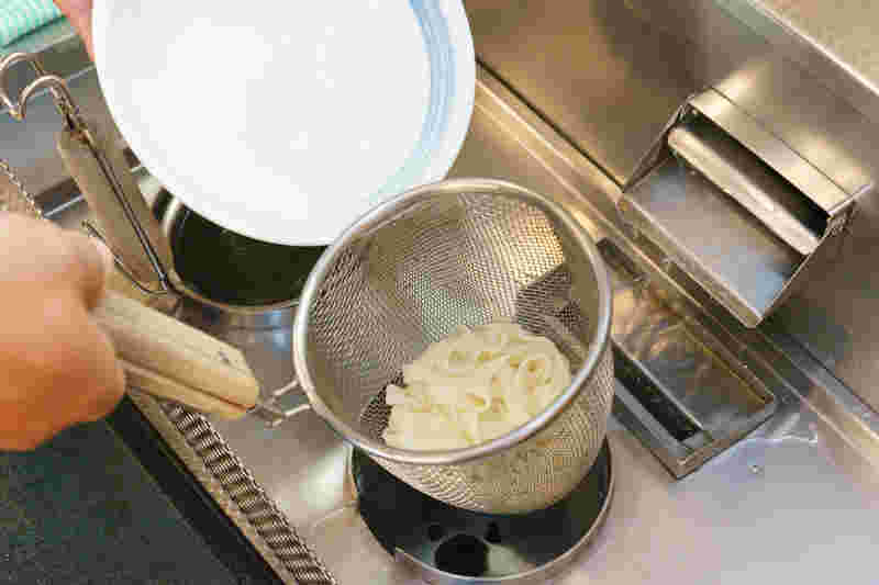 自分で麺を茹で器に盛りつけようとするところ