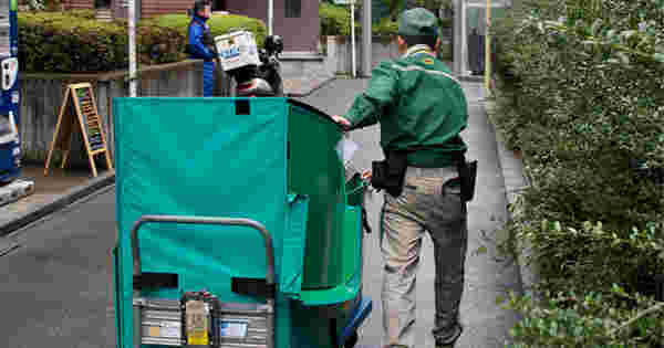 宅配グルマを引っ張るヤマト運輸配達員