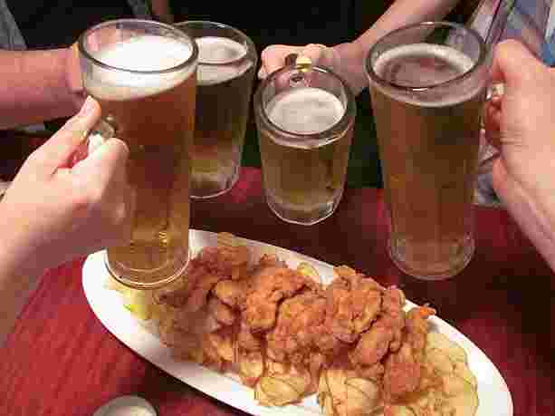 生ビールで乾杯する人とチキン