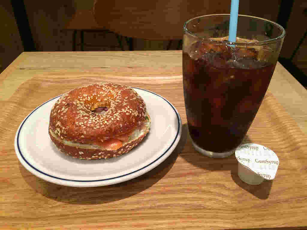 グラスに入ったアイスコーヒーと隣にベーグル