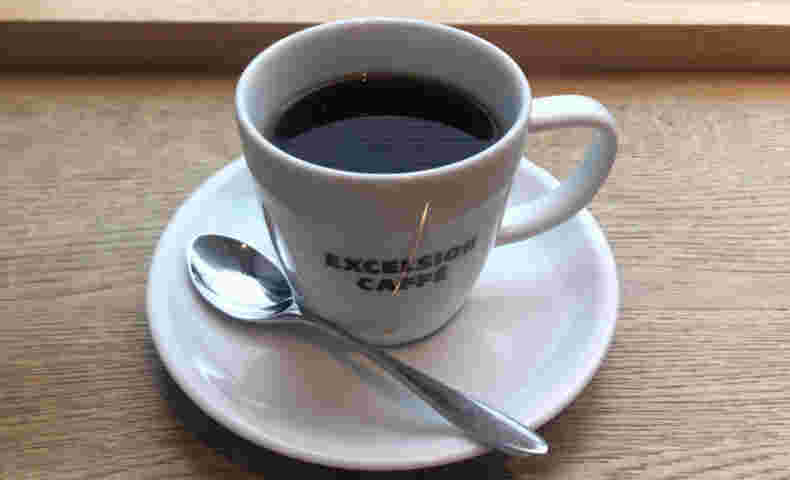白くロゴの入ったカップ＆ソーサーのコーヒー