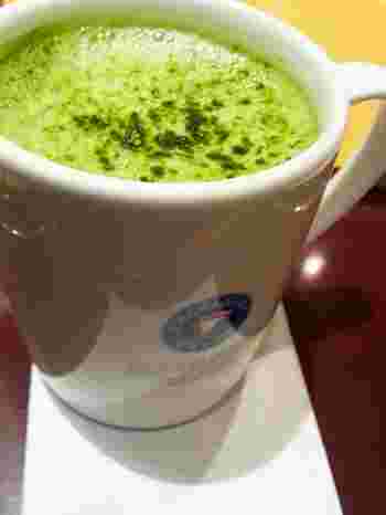 ロゴの入った白いマグカップに入った抹茶ラテ