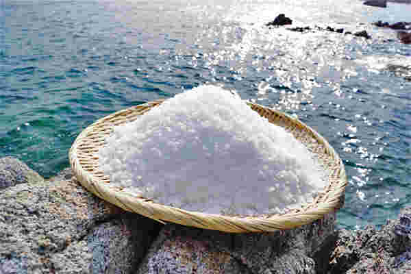 ざるに盛られた塩と、原料である海水