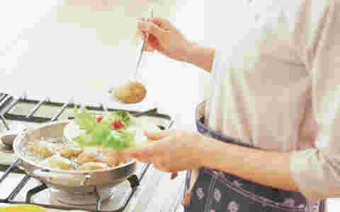 鍋を火にかけて料理をしている女性