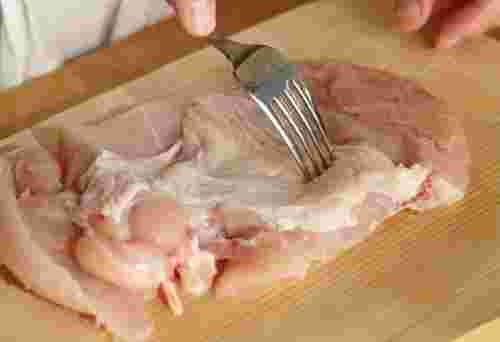 鶏肉にフォークを刺している画像