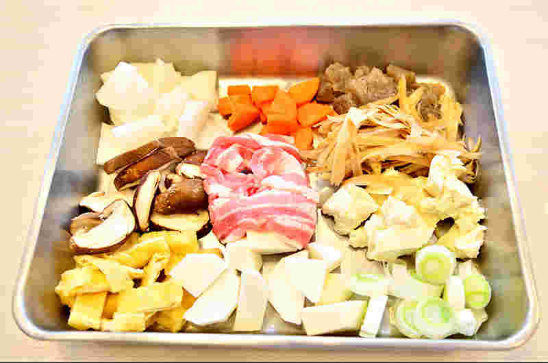 切ってバットに並べた豚汁の具材（豚肉、こんにゃく、油揚げなど）