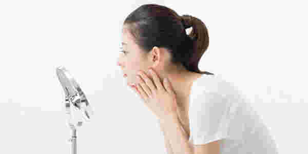 鏡を見て自分の肌を確認する女性
