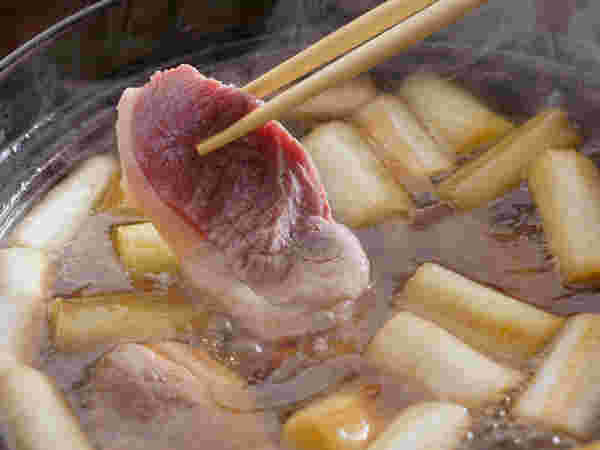 鴨鍋の鴨肉を持ち上げる画像