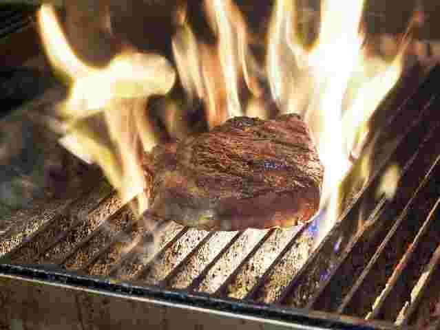 網の上で火に包まれて焦げている牛肉のステーキ