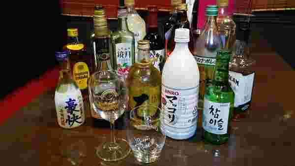 色々なお酒の瓶と二つのグラスが、テーブルの上に置かれている様子。