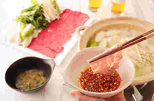 つけダレを手に持って肉をつけているところ