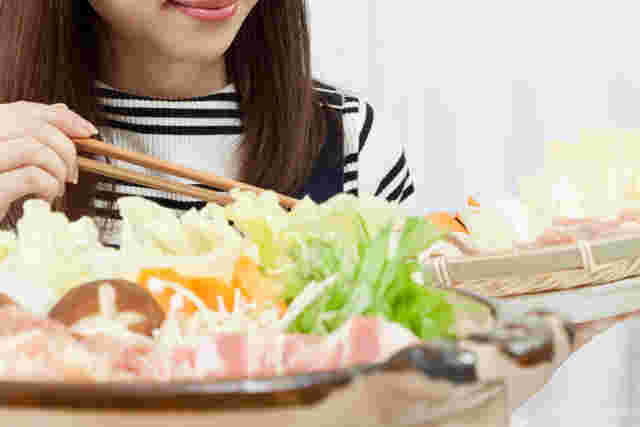鍋に具材を入れる女性