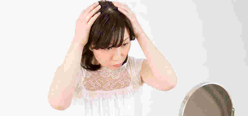 鏡を見ながら頭髪に両手を当てる