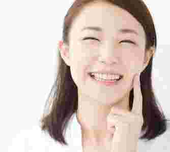 人差し指を頬に当てる笑顔の女性