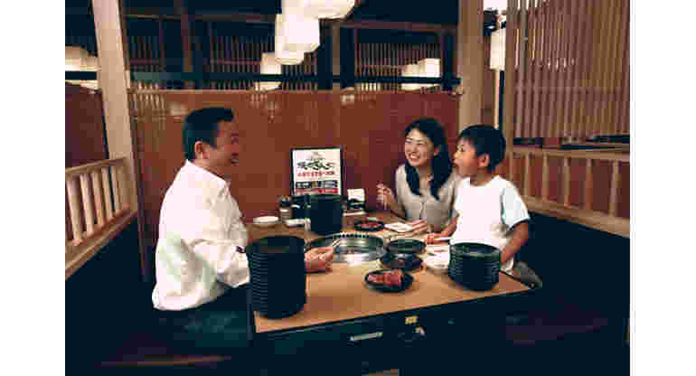 テーブルで焼肉を食べる子連れの夫婦らしき人たち