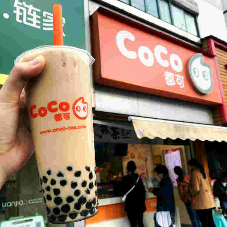 CoCo都可の店舗前に並ぶ人達。その手前にタピオカドリンクを手で持ってかざしている