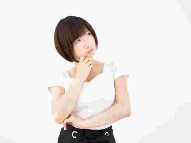 顎に手をつけ考えごとをしている白いシャツの女性