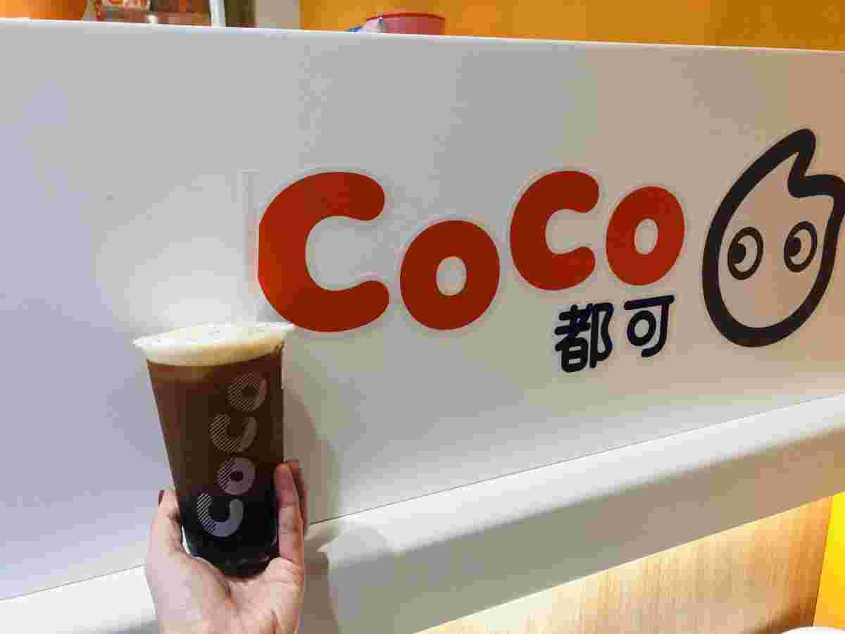 CoCo都可の看板近くに黒っぽいタピオカドリンクを乗せようとしている