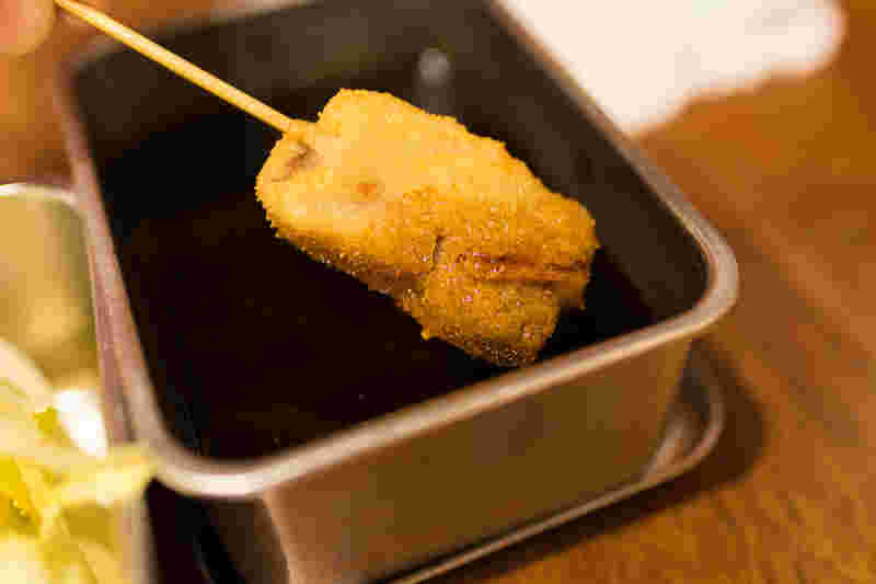 串カツにソースを付けている様子