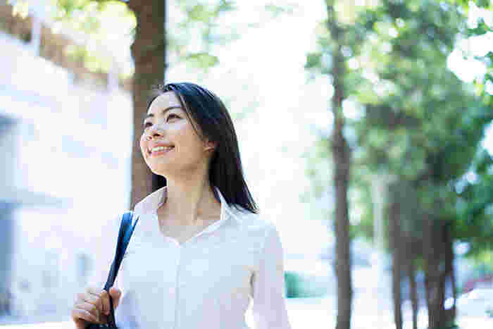 女性が並木通りを歩いているところ。