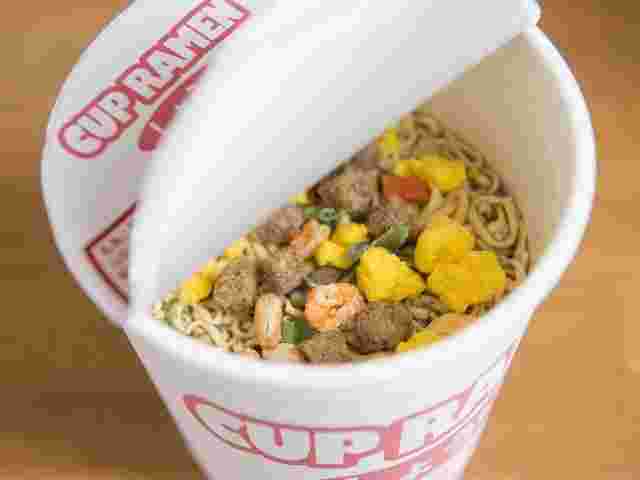カップラーメンのフタをあけている