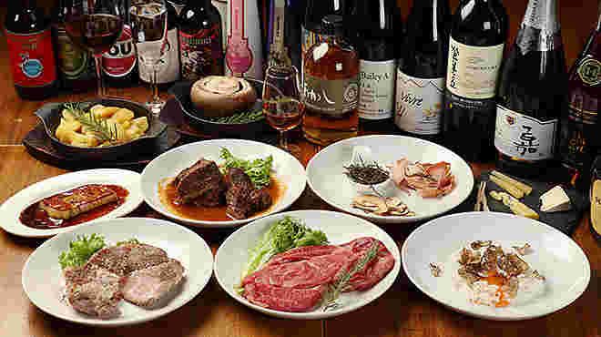 たくさんのお酒ボトルの前に料理が並べられている