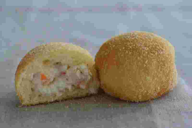 半分に切ったピロシキの断面から海老クリームの具が見えている様子