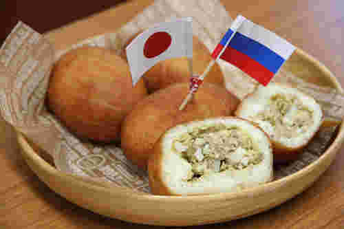 お皿に盛られた4個のピロシキに日本とロシアの国旗の飾りが付いている様子