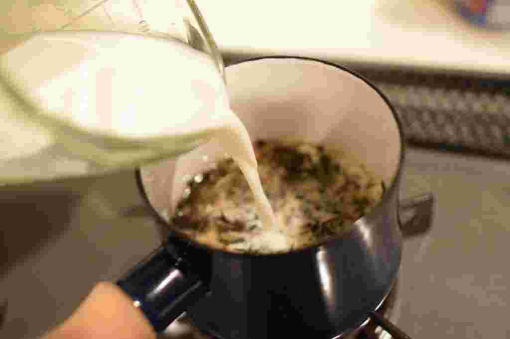 鍋で煮出したほうじ茶にミルクを加える様子