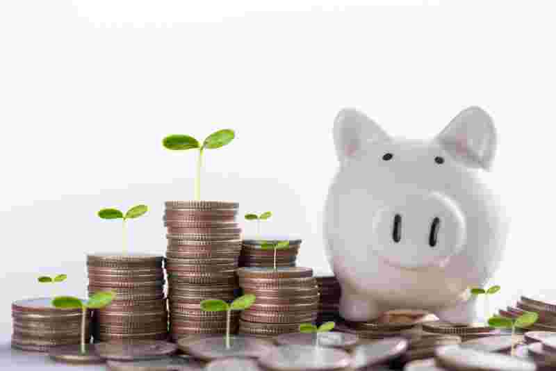 積み重なる小銭と白い豚の貯金箱