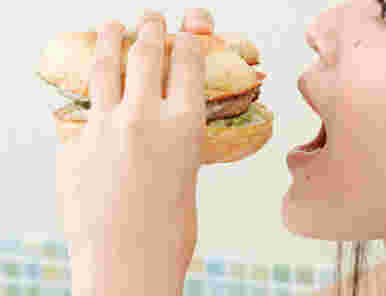 さかさまにしたハンバーガーを食べる女性