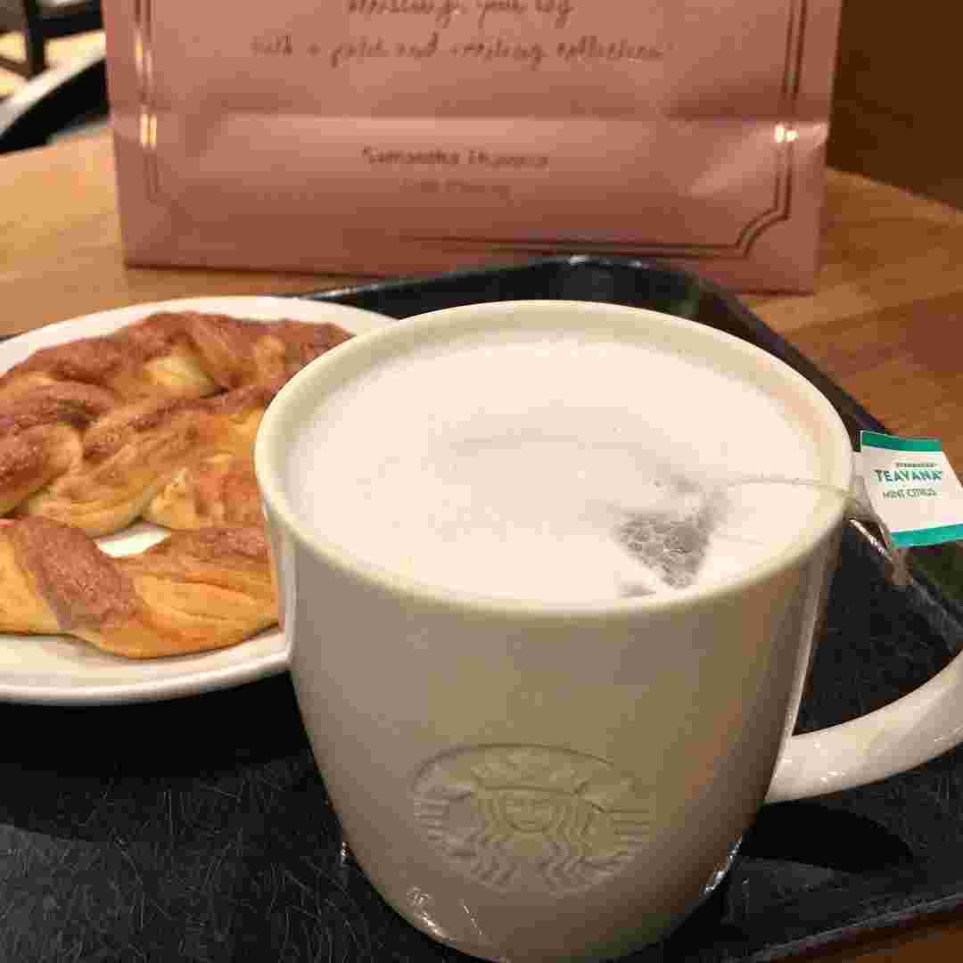 お盆の上に飲み物とパンが置かれている様。