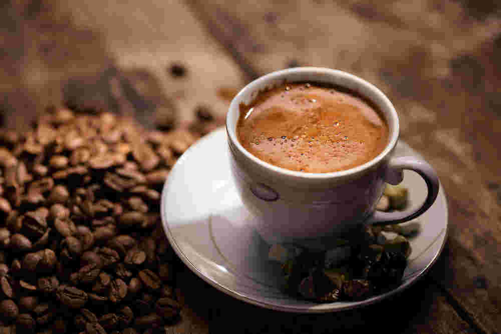 コーヒーと周りに散らばったコーヒー豆
