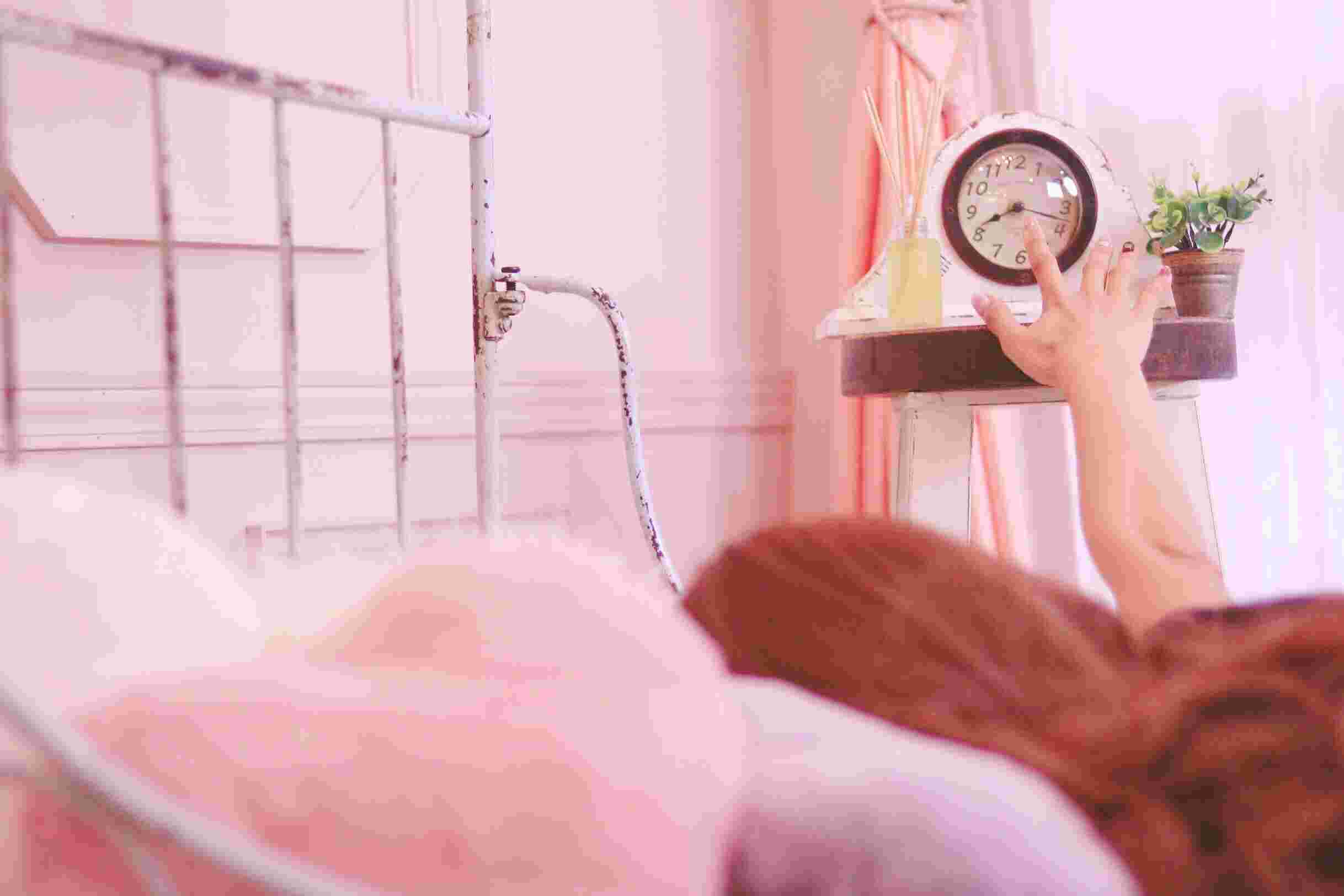 目覚ましを止めようと手を伸ばす女性
