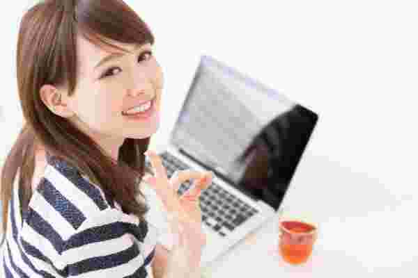 PCでネットショッピングをしながらOKサインを出してる笑顔の女性