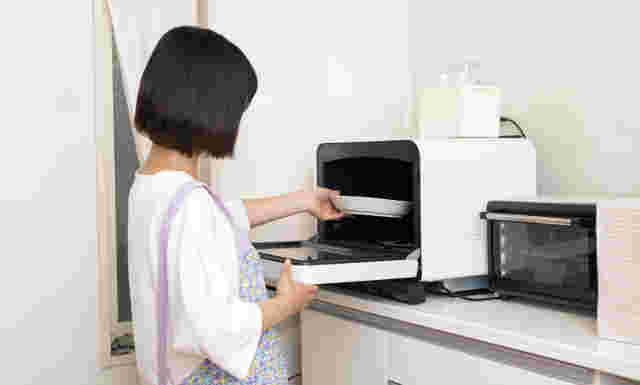 女性が電子レンジにお皿を入れている様子