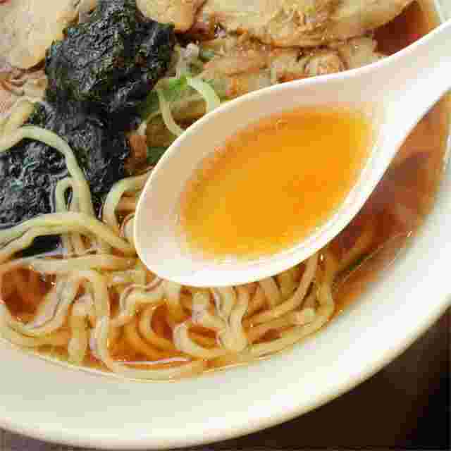 ラーメンのスープをレンゲですくっている様子