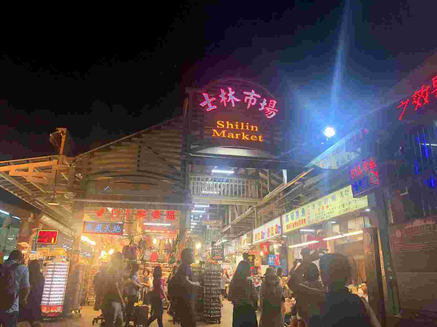 夜の明かりの付いた市場の賑わう風景。