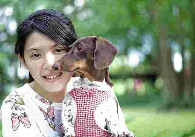 屋外で女性が犬を抱いているところ。