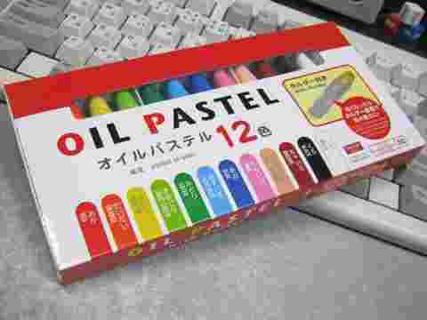 白いケースに入った12色のオイルチョークをキーボードの上に置いている様子