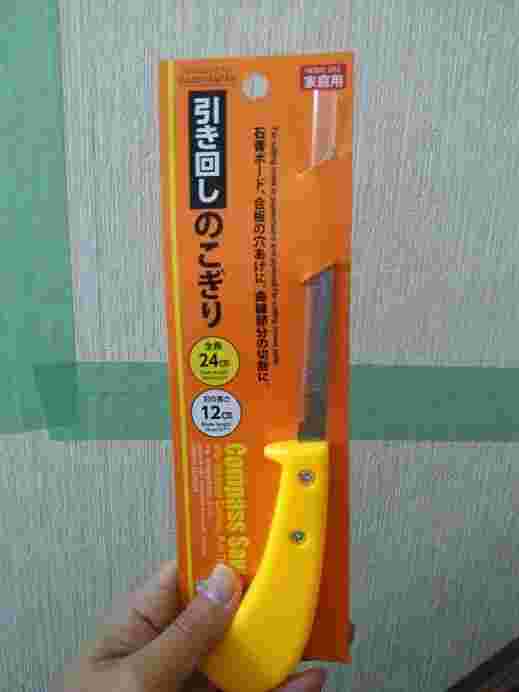 引き回しのこぎりを手に持っている