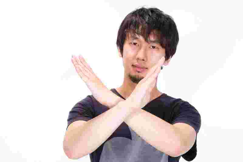 両手でバツマークを作っている男性