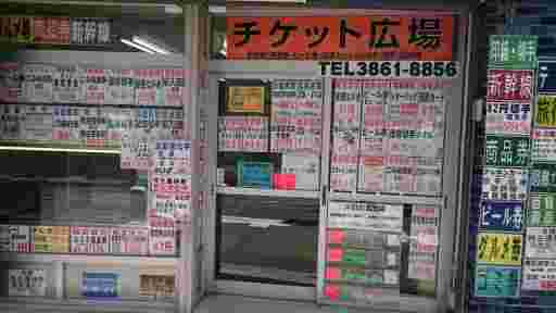 チラシがたくさん貼られた金券ショップの外観