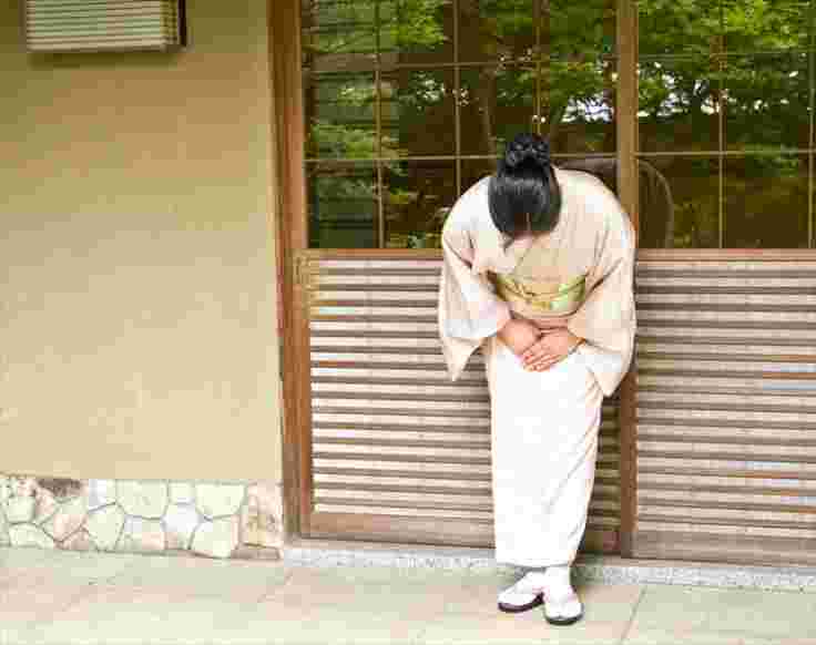 頭を下げている着物の女性