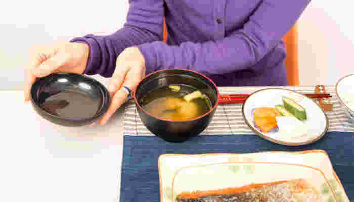 両手でお椀の蓋を開ける