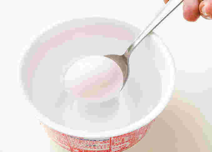 カップ麺の容器にタマゴを入れようとしている