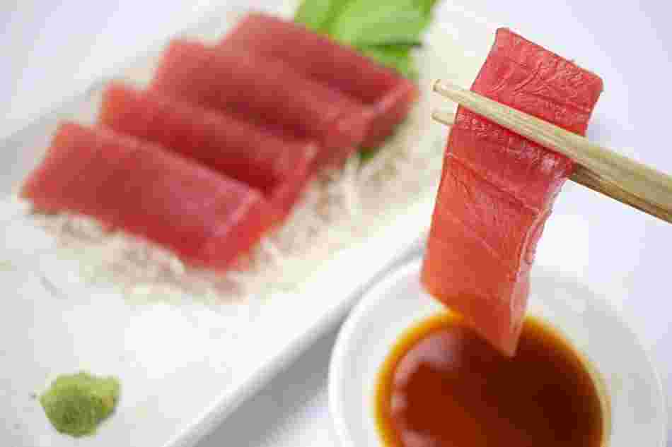 マグロの刺身を箸でつまんでいる様子