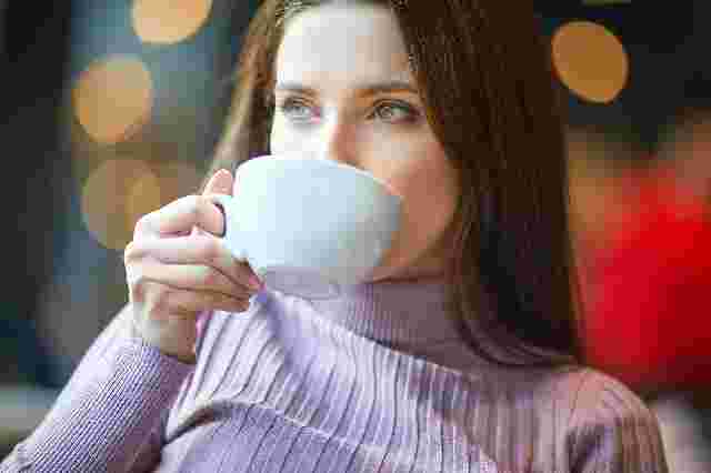 白いカップで豆乳コーヒーを飲んでいる女性