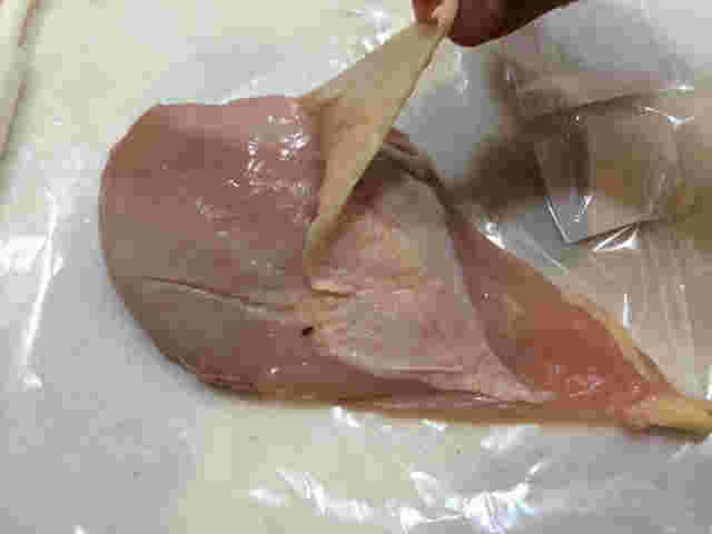 鶏のむね肉の皮をはいでいる
